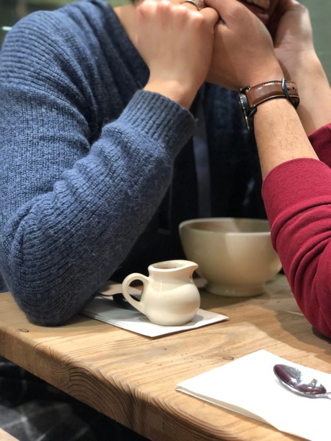 A couple embrace in a coffee shop. Her hands are holding his face, his face is just out of shot.
