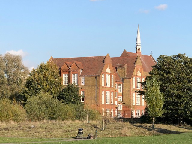 A big old school building surrounded by trees and grass.