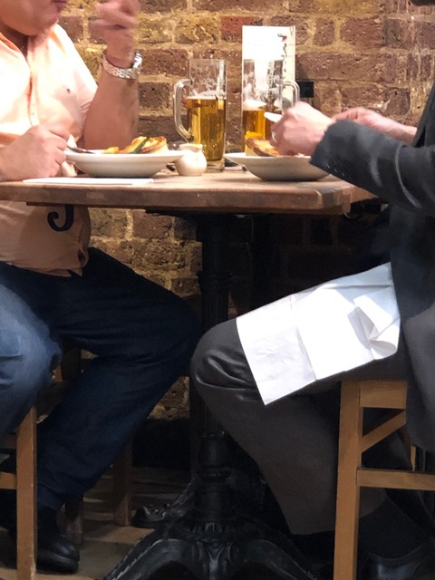 Two men eating pies and drinking beer in a cafe.