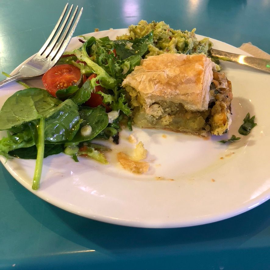 A healthly looking salad and slice of vegetable pie on a plate half eaten